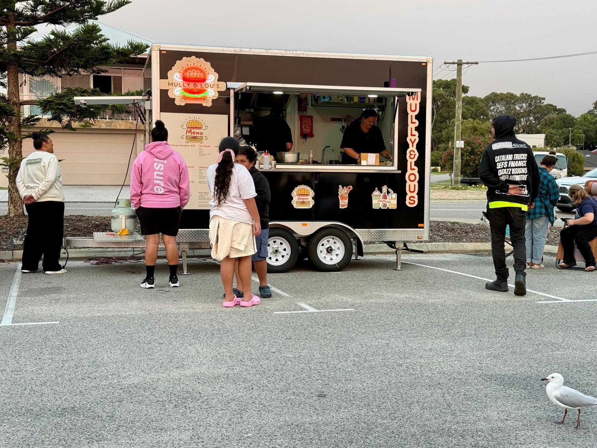 The Mully & Lou's van serving a community event with a line of guests